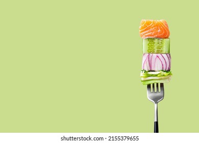 Close-up of fork with food on it: delicious fillet salmon, cucumber, onion, green salad on green background. Concept of healthy diet and clean eating, balanced nutrition space for text - Shutterstock ID 2155379655