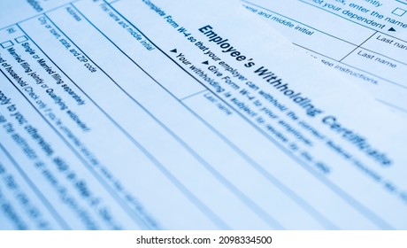 A closeup of the Form W-4, Employee's withholding certificate, and a fountain pen on a wooden surface - Shutterstock ID 2098334500
