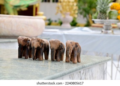 Closeup of Four carved wooden elephants are placed on a marble floor inside a Thai Buddhist temple in Thailand. It is the belief of Thai Buddhists. for a healthy body. - Powered by Shutterstock