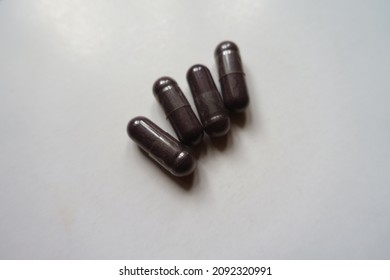 Closeup Of Four Dark Purple Capsules Of Bilberry Extract Dietary Supplement