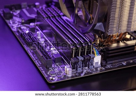 Close-up of four DDR RAM modules on a computer motherboard. CPU cooler fan, metal heatsink fins, and a power connector are visible