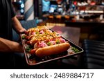 Close-up of four garnished hot dogs on a tray, with various toppings