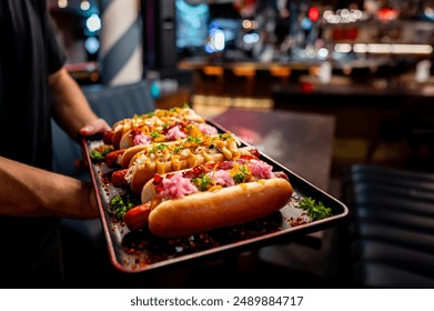 Close-up of four garnished hot dogs on a tray, with various toppings - Powered by Shutterstock