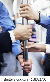 Close-up Of Four Hands Holding Pole On Subway