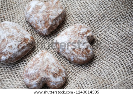Close-up of four heart-shaped  gingerbread cookies in a sugar glaze lying on a linen cloth top view
