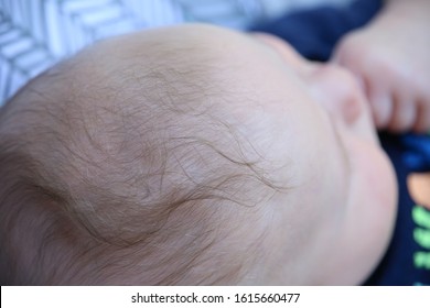 Close-up Of Four Month Old Baby Boy With Bright Blue Eyes And Fingers In Mouth Or Folded Nicely On The Chest In Bouncy Seat