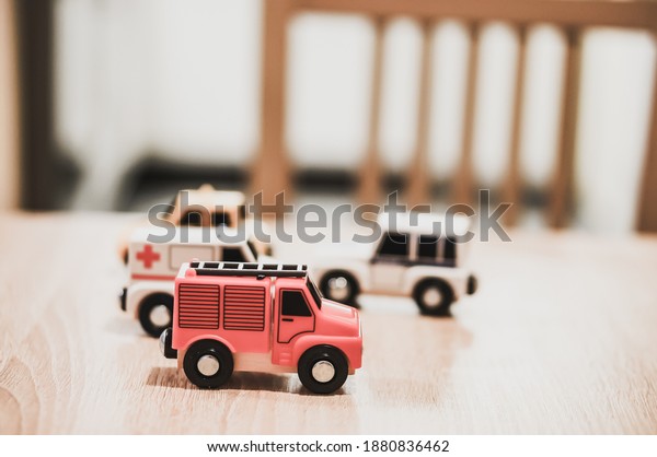 A closeup of four tiny cars:\
emergency, firetruck, police and taxi toys on a wooden\
table