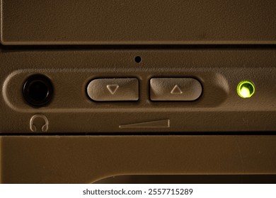 A close-up of a fragment of a 1990s computer interface with a headphone jack and volume buttons.