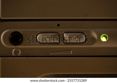 A close-up of a fragment of a 1990s computer interface with a headphone jack and volume buttons.