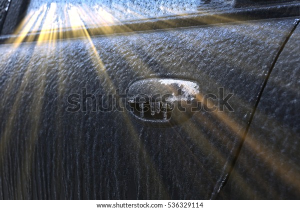 closeup fragment of the ice-covered car in the\
sun frosty morning