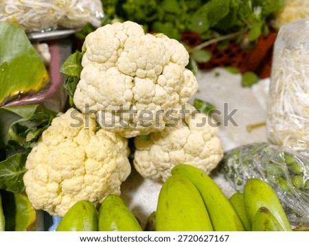 Close-up of fresh cauliflower and assorted vegetables displayed at market. Perfect for food, cooking, and healthy themes.