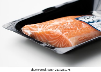 Closeup Of Fresh Farmed Atlantic Salmon Fillet In Orange Color With Clear White Veins In A Vacuum Sealed Plastic Container Isolated On A White Background.