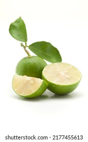 Close-up Of Fresh Green Organic Lemon (Citrus Limon) And Sliced Lemon  With Leaf  Isolated Over White.

