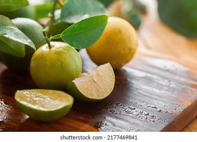 Close-up of fresh green and yellow  organic lemon (Citrus limon) and slices and pieces of lemon on a wooden cutting board with green leaf. - Shutterstock ID 2177469841