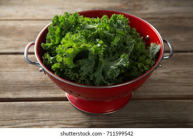 Close-up of fresh kale in red colander on wooden table - Powered by Shutterstock