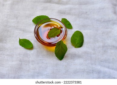 Close-up Of Fresh Leaves Of Holy Basil Or Tulsi With Raw Honey, The Home Remedy To Cure Diseases For Asthma Attacks And For Coughs. Green Tea Ingredients, Tulsi, And Honey On White Background.