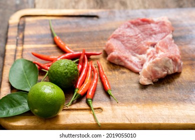 A Closeup Of Fresh Meat, Chili And Lime On A Wooden Boar