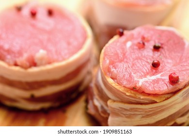 Closeup Of Fresh Raw Bacon Wrapped Pork Tenderloin Medallions Sprinkled With Whole Red Pepper.