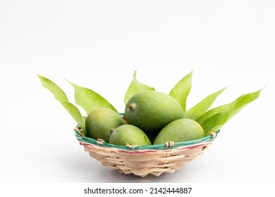 Closeup Of Fresh Raw Green Mangoes Also Called Kacha Khatta Aam With Leaves In Bamboo Basket. Isolated On White Background With Copy Space