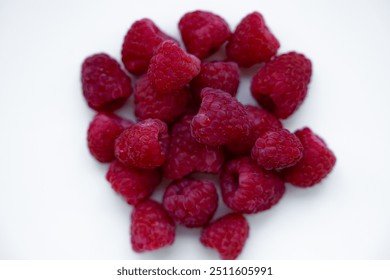 A close-up of fresh, ripe raspberries hanging on green stems, showcasing their vibrant red color and juicy texture, perfect for a healthy summer snack - Powered by Shutterstock