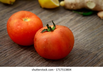 Close-up Of Fresh, Ripe Tomatoes On Wooden Table, Garlic, Lemon And Ginger In Background