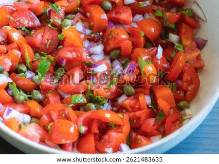 Close-up of fresh salsa made with cherry tomatoes, red onion, capers, and parsley, served in a bowl. The colorful mix of ingredients gives a vibrant and healthy look
