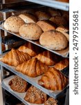 Close-up of freshly baked bread and croissants displayed on a rack in a bakery. Variety of baked goods.