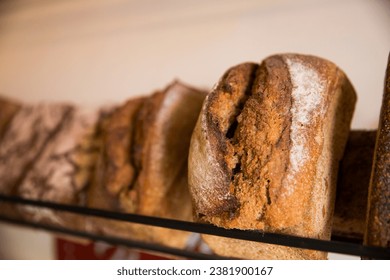 Close-up of freshly baked rustic bread loaves displayed on a shelf, showing the rich texture and details