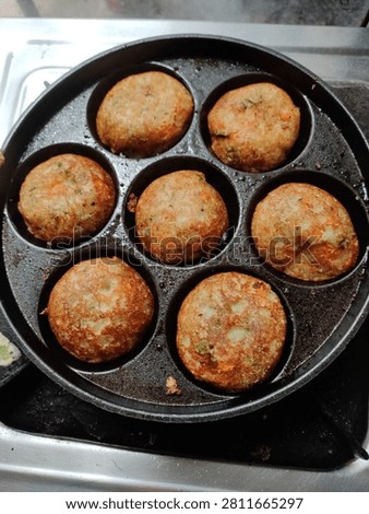 Close-up of freshly cooked vegetable appe (paniyaram or paddu) in a traditional cast-iron appe pan. These golden-brown South Indian savory snacks are prepared with a fermented batter and vegetables, making them a delicious homemade breakfast or snack.