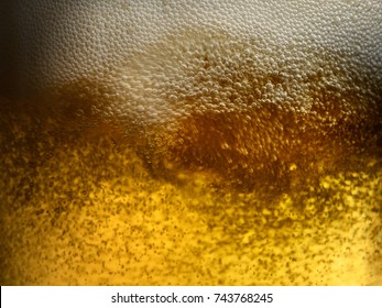 Closeup Of Freshly Poured Gold Amber Beer With Frothy Head And Carbonation Bubbles