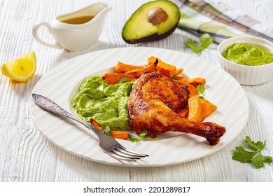 Close-up Of Fried Chicken Leg With Guasacaca Sauce Of Avocado, Green Pepper And Herbs And Sweet Potato Chips On White Plate On Wooden Table, Horizontal View From Above