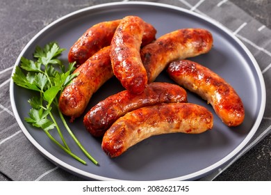close-up of fried sausages, bangers on a plate on a concrete table, horizontal view from above