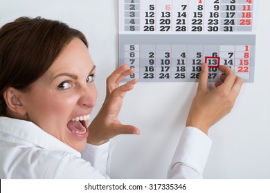 Close-up Of Frightening Businesswoman Marking Friday 13 On Calendar