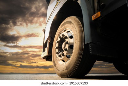 Close-up, Front a big truck wheel, tire of semi truck parked at sunset sky. Industry freight truck transportation.