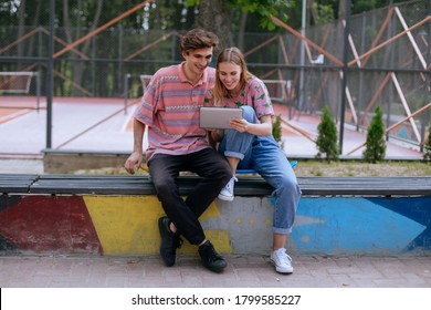 Closeup in front of the camera one couple enjoying the time outside in park they watching something on the electronic tablet and analyzing together some ideas - Powered by Shutterstock