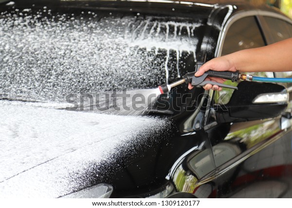 Closeup of front side of black car cleaning,\
washing by high pressure foam and soap spraying before rubbing to\
remove dust and dirty\
thing.