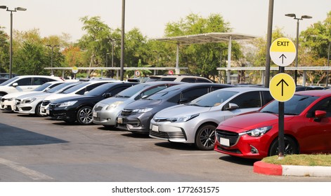 Closeup of front side of red car with  other cars parking in outdoor parking area with natural background in bright sunny day.