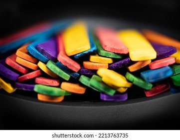 Close-up Front View Of Colorful Popsicle Sticks In A Black Bowl On A Black Background. Concept Of Children's Art Or Imagination For Kids.