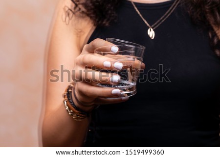 A closeup and front view on a young woman suffering from Parkinson's disease, the wrist and hand tremors whilst trying to drink, the disorder usually affects the elderly.