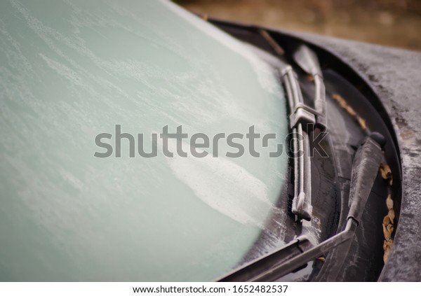 Close-up\
of frosted car wipers and frozen car windshield. Spring frosts and\
frozen car. Metal and plastic parts of the\
car.