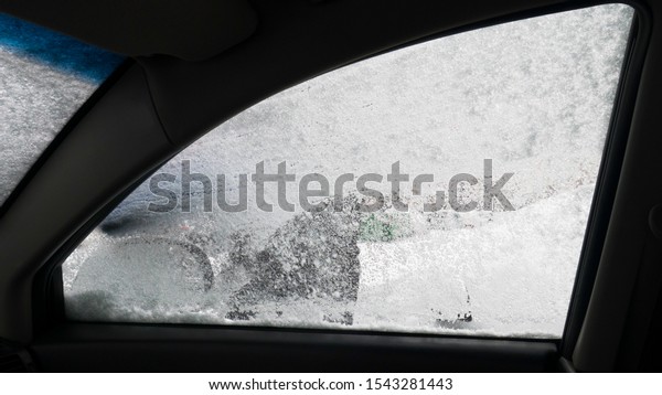 Closeup of frozen car window under a layer of snow -\
view from inside the\
car.