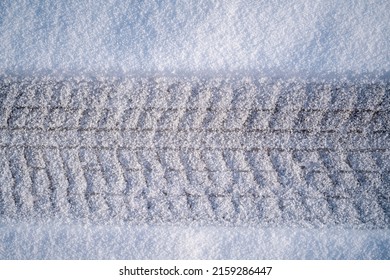 A closeup of a frozen tire track with new snow over it