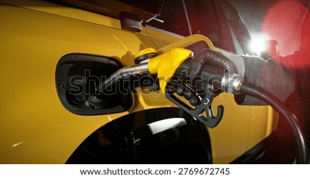 Close-up of fuel nozzle inserted into car tank. Refueling process, automotive energy, transportation and fuel service concept with dramatic lighting.