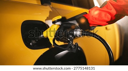 Close-up of fuel nozzle inserted into car tank. Refueling process, automotive energy, transportation and fuel service concept with dramatic lighting.