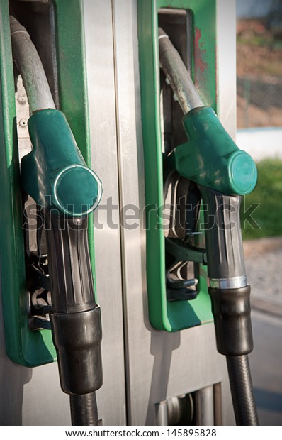 Closeup\
of fuel nozzles at a gas station. Gritty look.\
