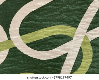 Close-up full frame texture of an abstract wavy pattern featuring white and light green curved lines printed on a dark green fabric surface.
