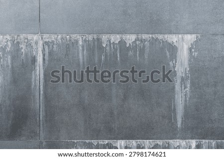 Close-up full frame texture of white efflorescence salt stains and water leaks on a dark gray artificial stone facade panel. Abstract industrial background showing building defect, moisture damage, poor waterproofing, and weathered concrete masonry surface