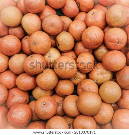 A close-up full frame view of a pile of fresh oranges displayed at a local fruit market stall in Tuban, East Java, Indonesia. Ripe citrus fruit texture background.