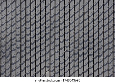 Close-up full frame view of a section of a chainlink fence filled gray vertical slats
