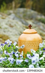 Closeup Of Funerary Urn Surrounded By Blue Violets Ready For Spreading Of The Ashes In The Woods